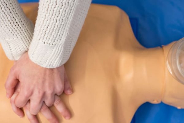 istruttore mostra il massaggio cardiaco con l'aiuto di un manichino