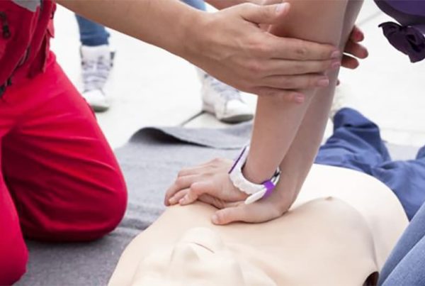 istruttore primo soccorso insegna massaggio cardiaco ad un corsista con un manichino